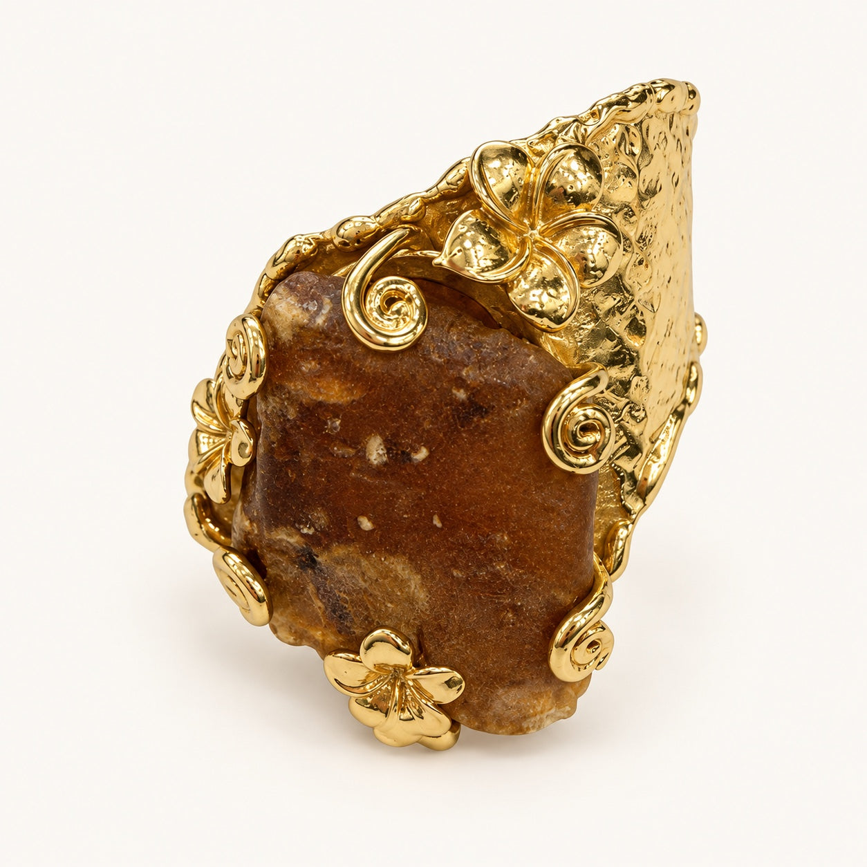 Anello floreale color oro e marrone, vista frontale con dettaglio centrale irregolare, fiori e motivi a spirale.