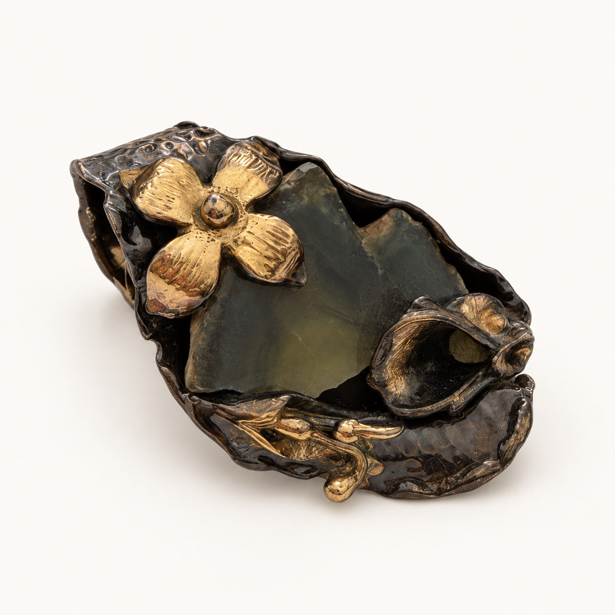 Anello con fiore a quattro petali visto a tre quarti, con dettagli botanici curvi e superficie scura.