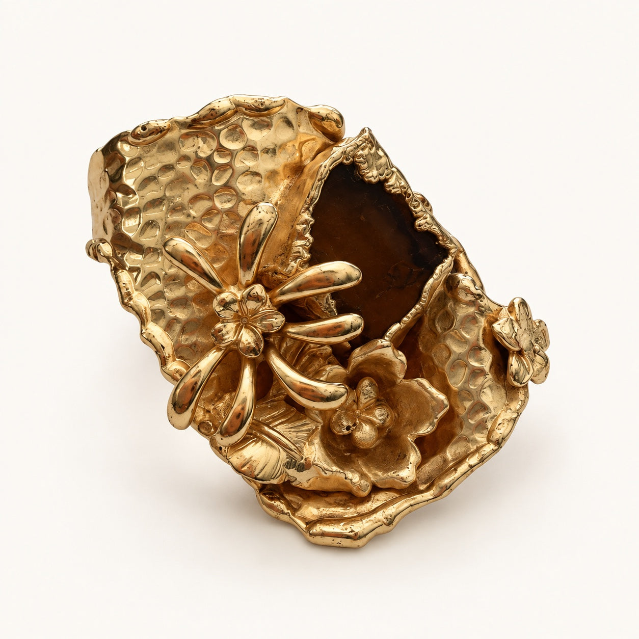 Anello con margherita visto a tre quarti, con frontale asimmetrico martellato e cornice color oro.