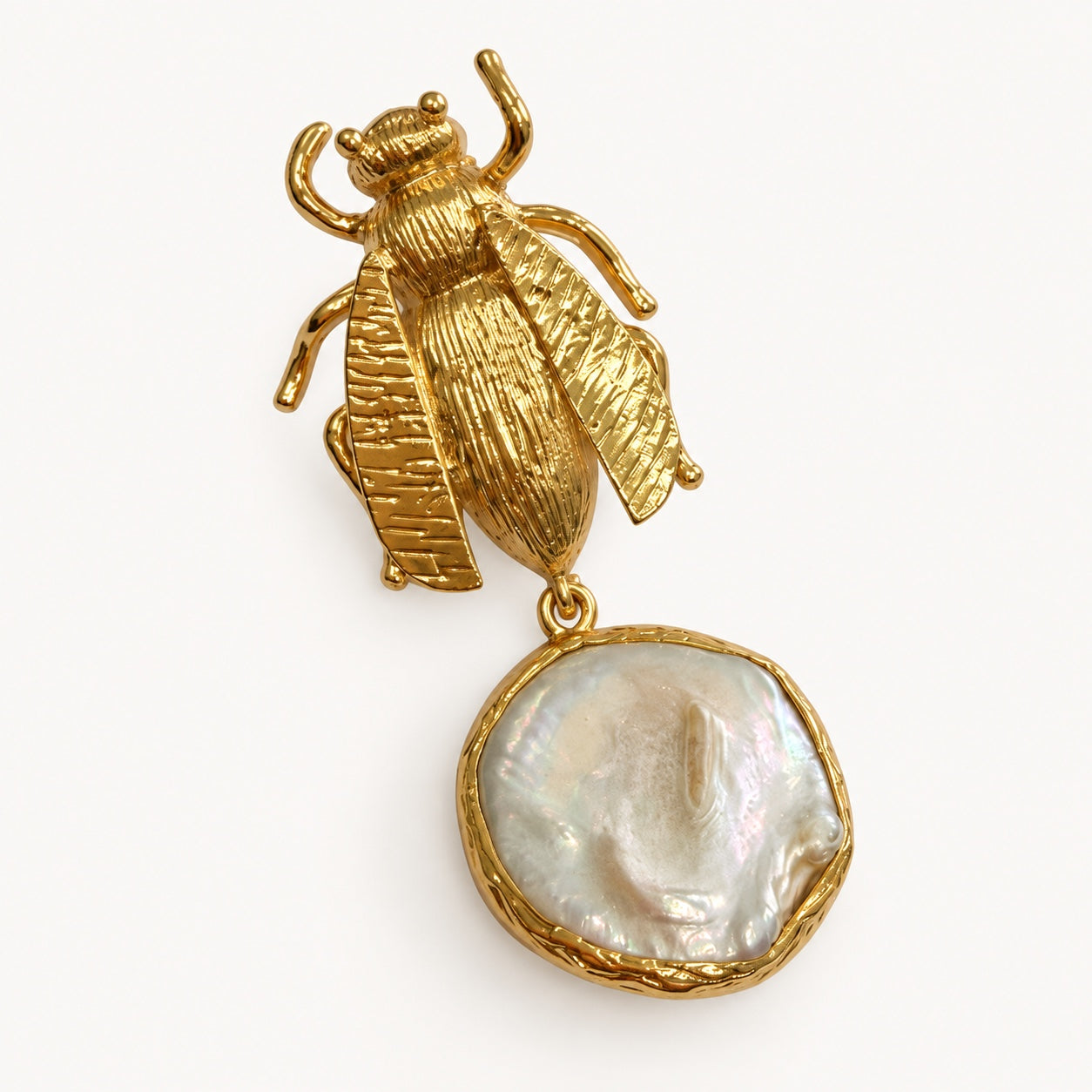 Dettaglio di un orecchino con insetto alato color oro e pendente bianco iridescente dalla superficie ondulata.