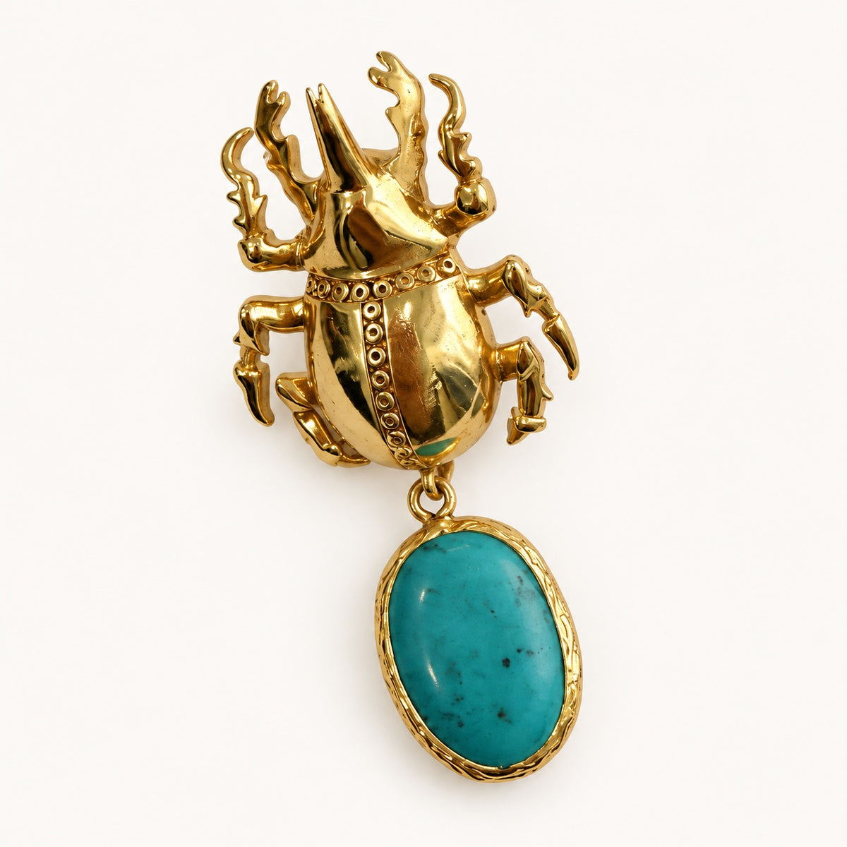 Dettaglio di un orecchino a scarabeo color oro, con corpo decorato e pendente ovale color turchese.