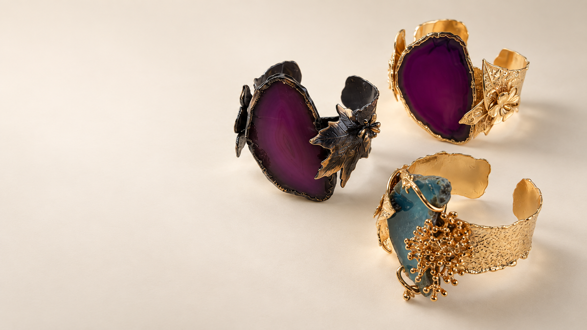 Tre bracciali Philo P nei toni viola e blu, con finiture dorate e scure, su fondo avorio